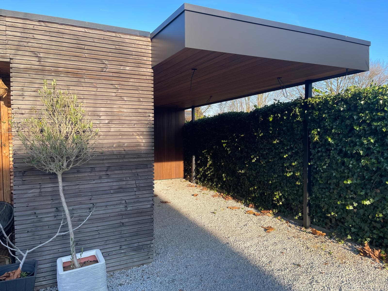 Carport aansluitend op de bestaande tuinberging met haag en grindpad