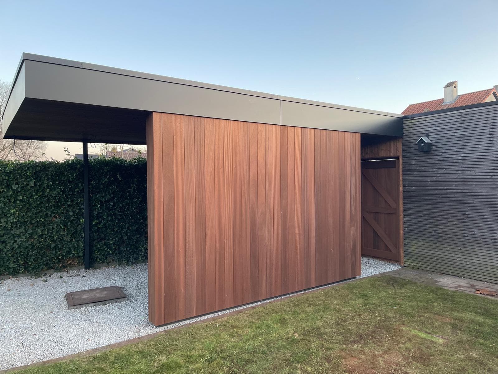 Moderne carport met Ayous thermo houten gevel en zwarte trespa dakrand, WoPa Construction