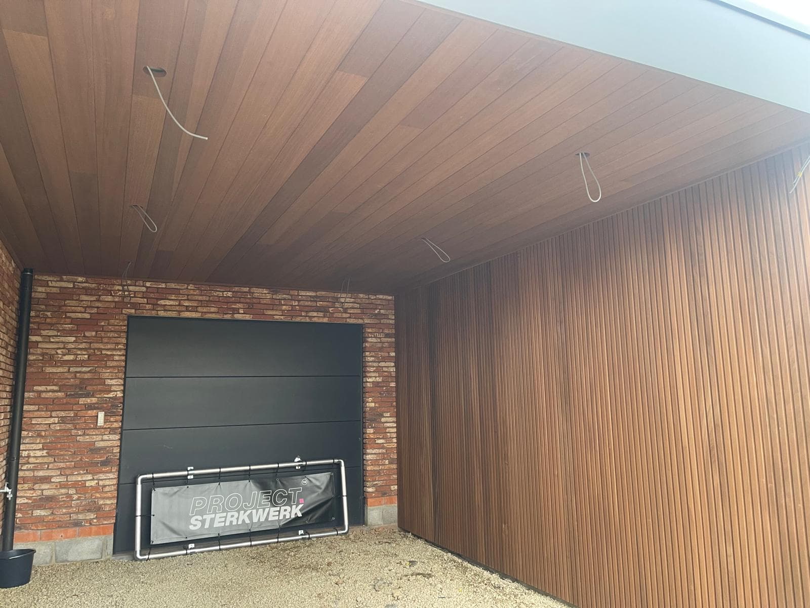 Carport binnenzijde met combinatie van Ayous thermo hout, baksteen en zwart boeiboord