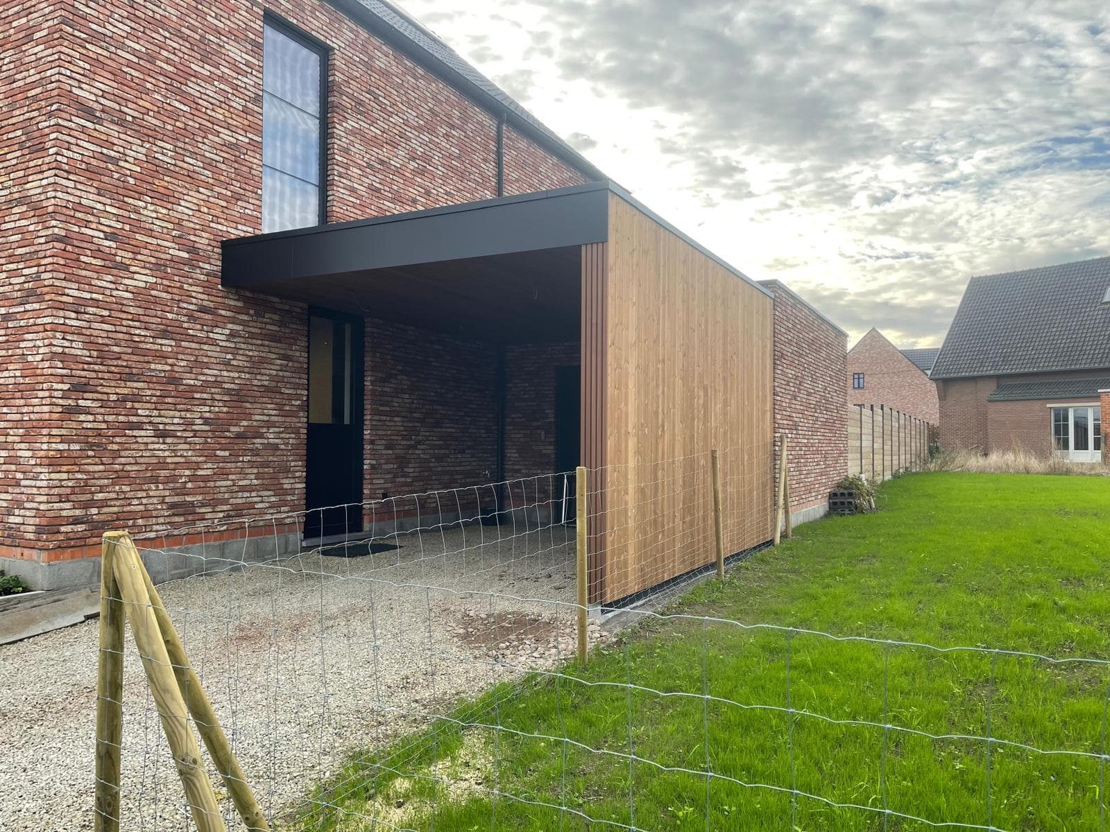 Aangebouwde carport met Ayous thermo houten gevel en zwarte trespa boeiboord, WoPa Construction