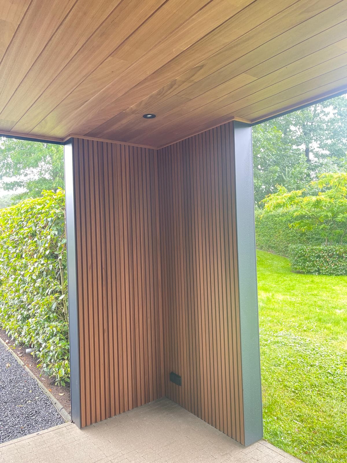 Hoekdetail waar het Ayous thermo houten plafond overgaat in de verticaal geribde houten wand met inbouwspot