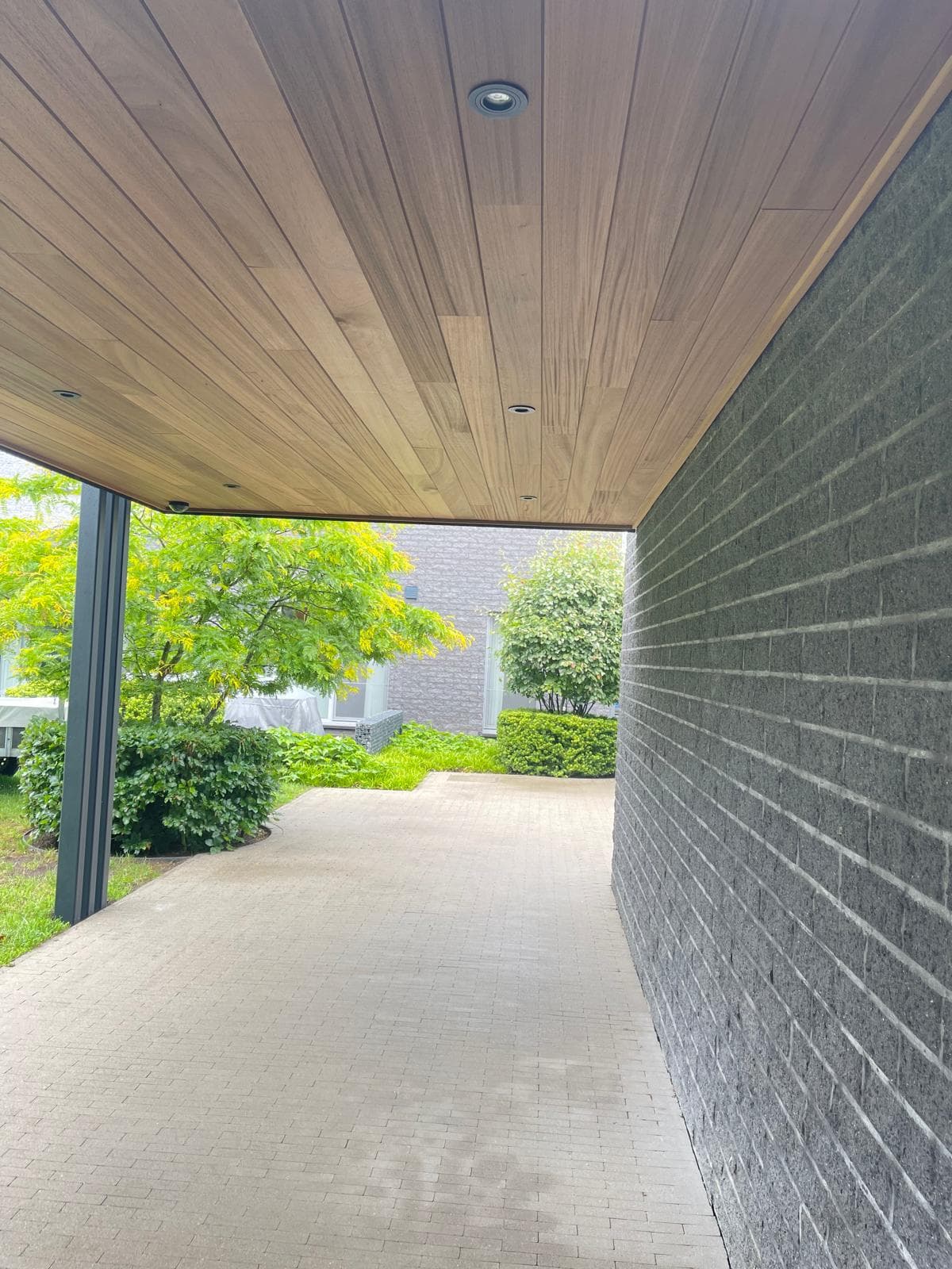 Detail van het Ayous thermo houten plafond met inbouwspot langs de donkere gevelsteenwand