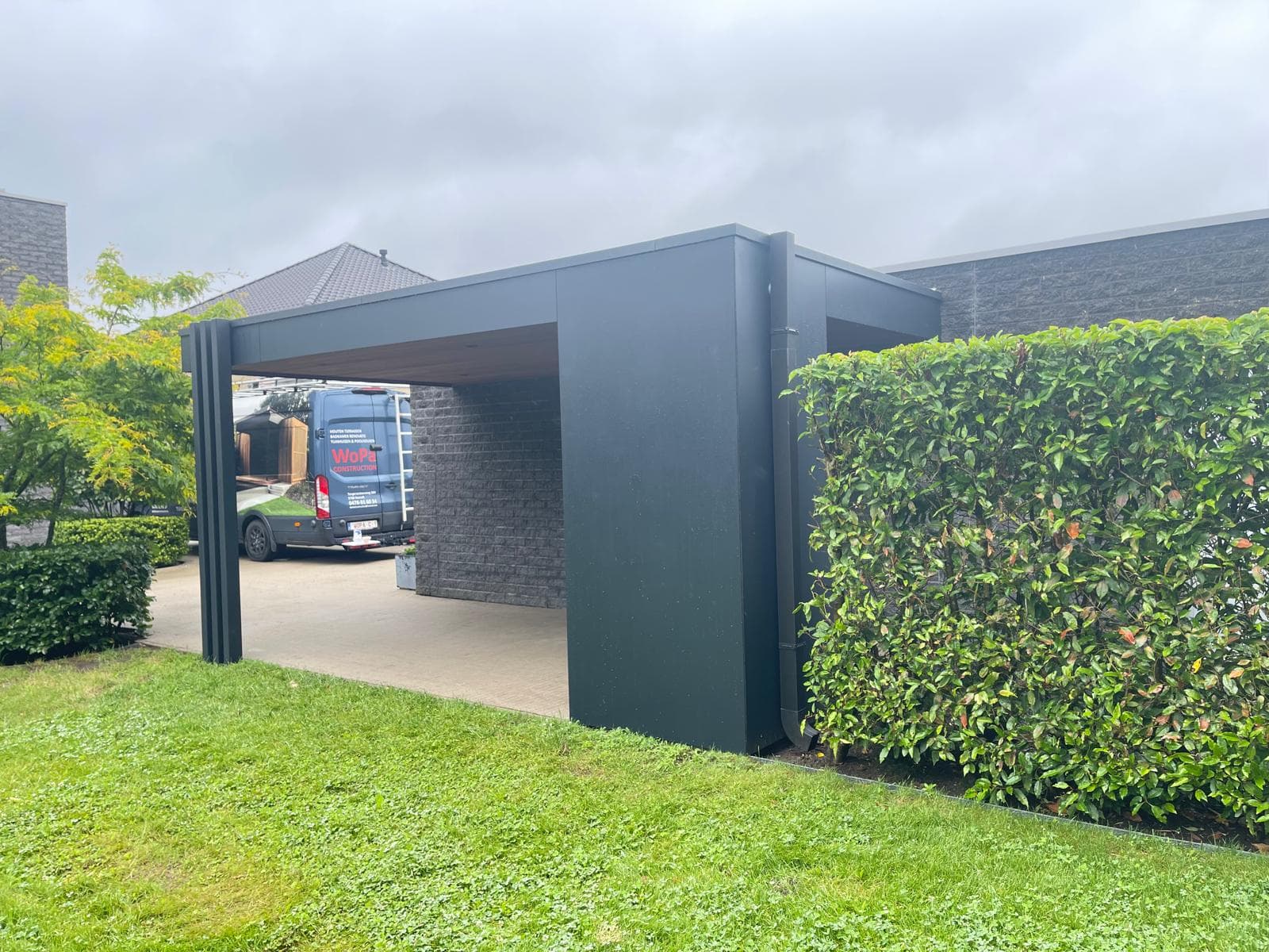Carport in wintergebruik met een bestelwagen geparkeerd onder het zwarte trespa volume