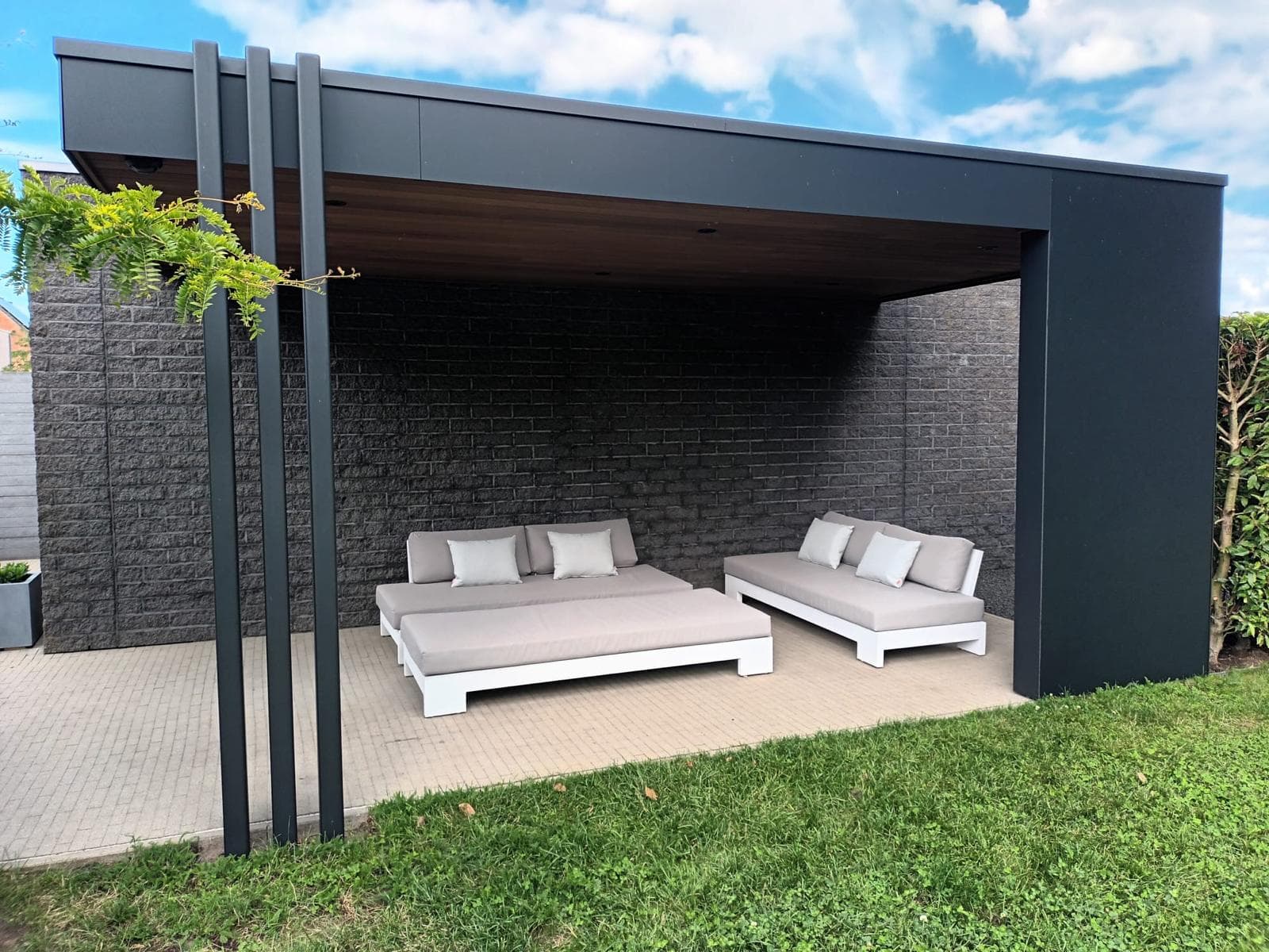 Carport met zomerse loungehoek onder een Ayous thermo houten plafond en zwarte trespa dakrand, WoPa Construction