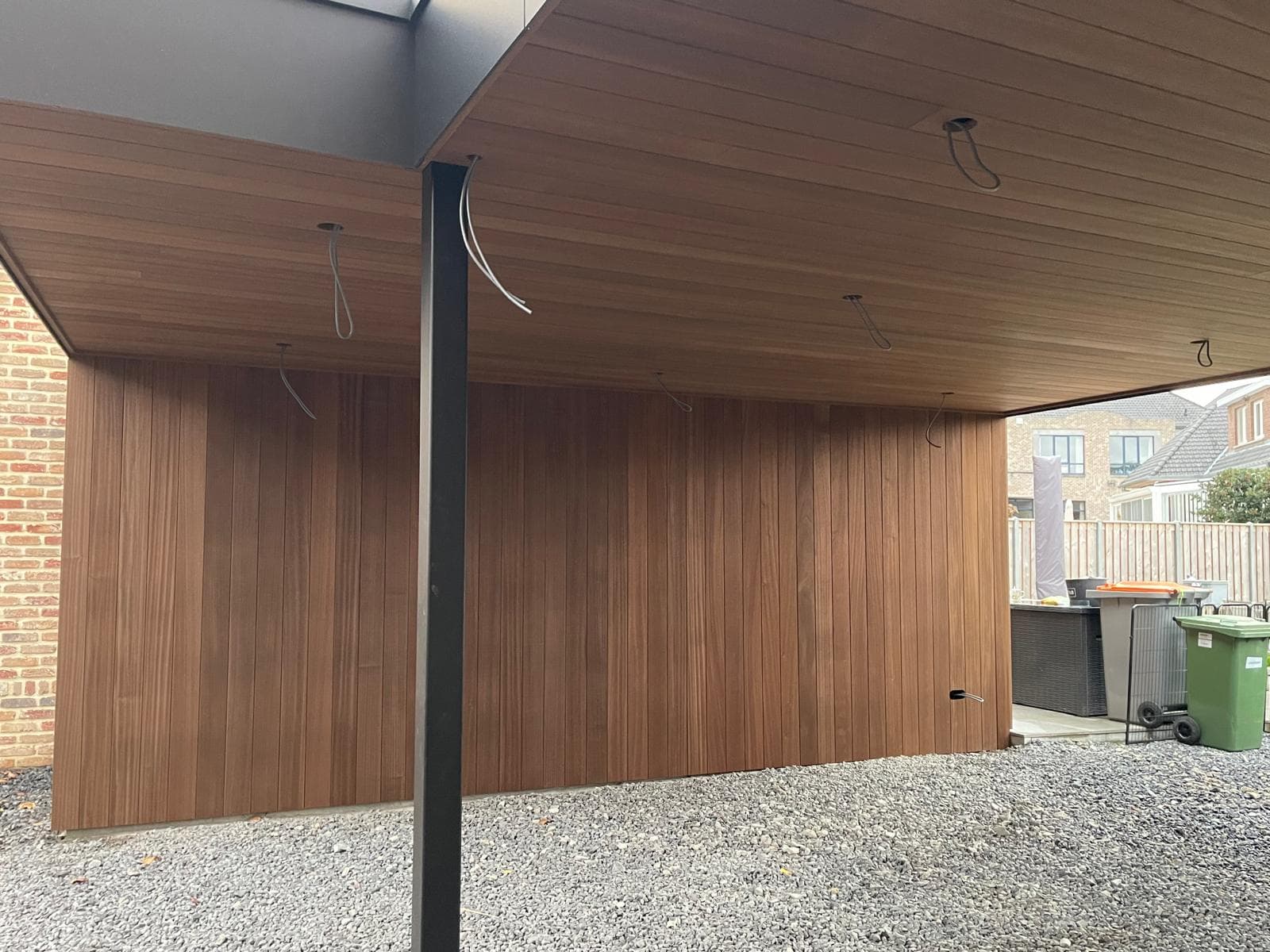 Houten Ayous-thermowand en plafond onder de carport met zwarte stalen kolom