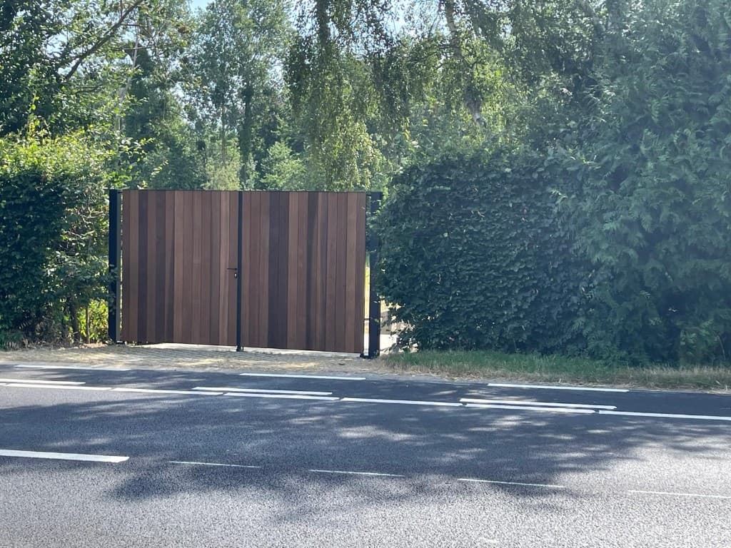 Inrijpoort vanaf de straat: Ayous thermo tussen hagen aan de asfaltweg