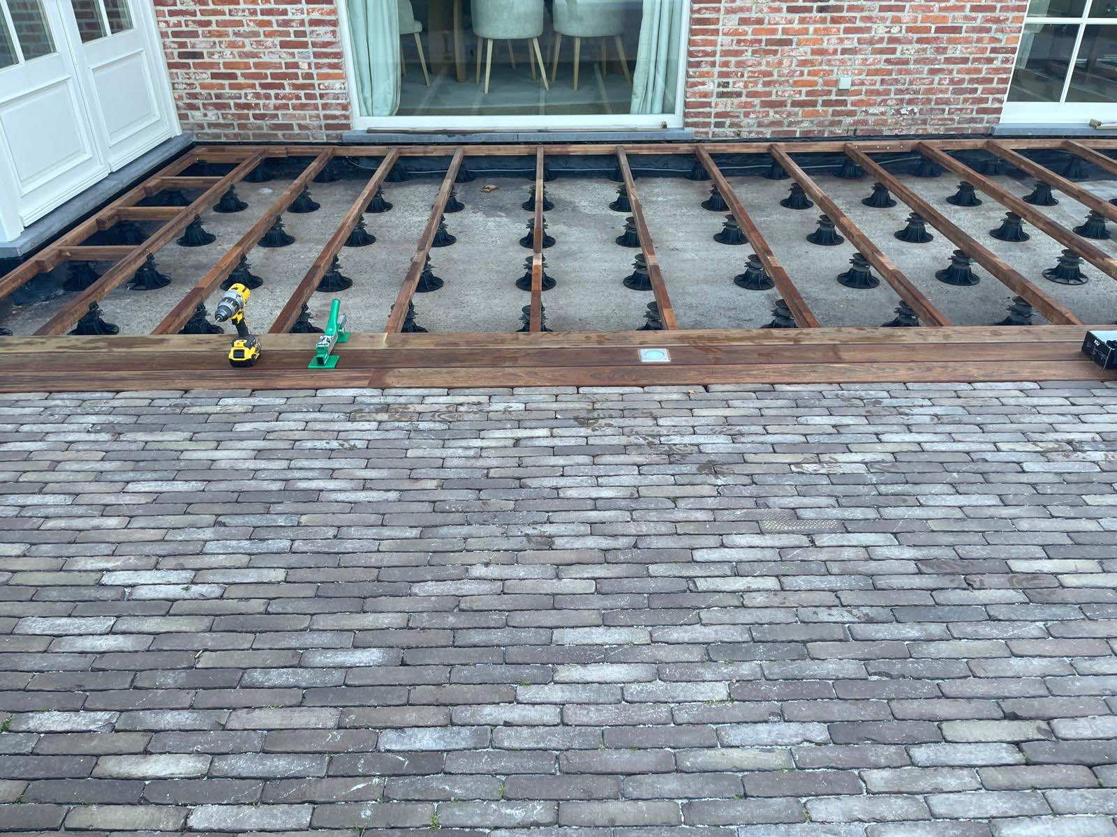 Onderconstructie van het IPE-terras op zwarte verstelbare kunststof tegeldragers tijdens de aanleg