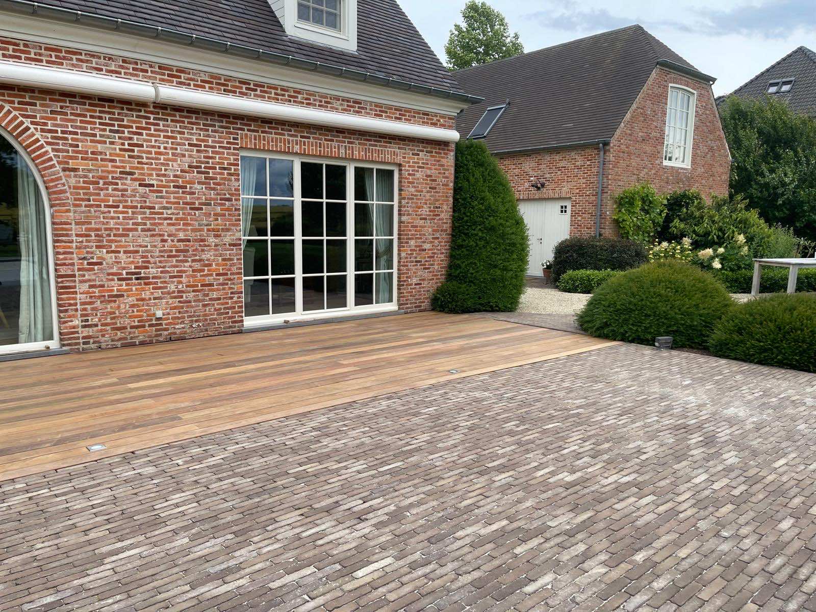 Overzicht van het IPE-terras dat naadloos aansluit op de klinkerverharding naast de villa
