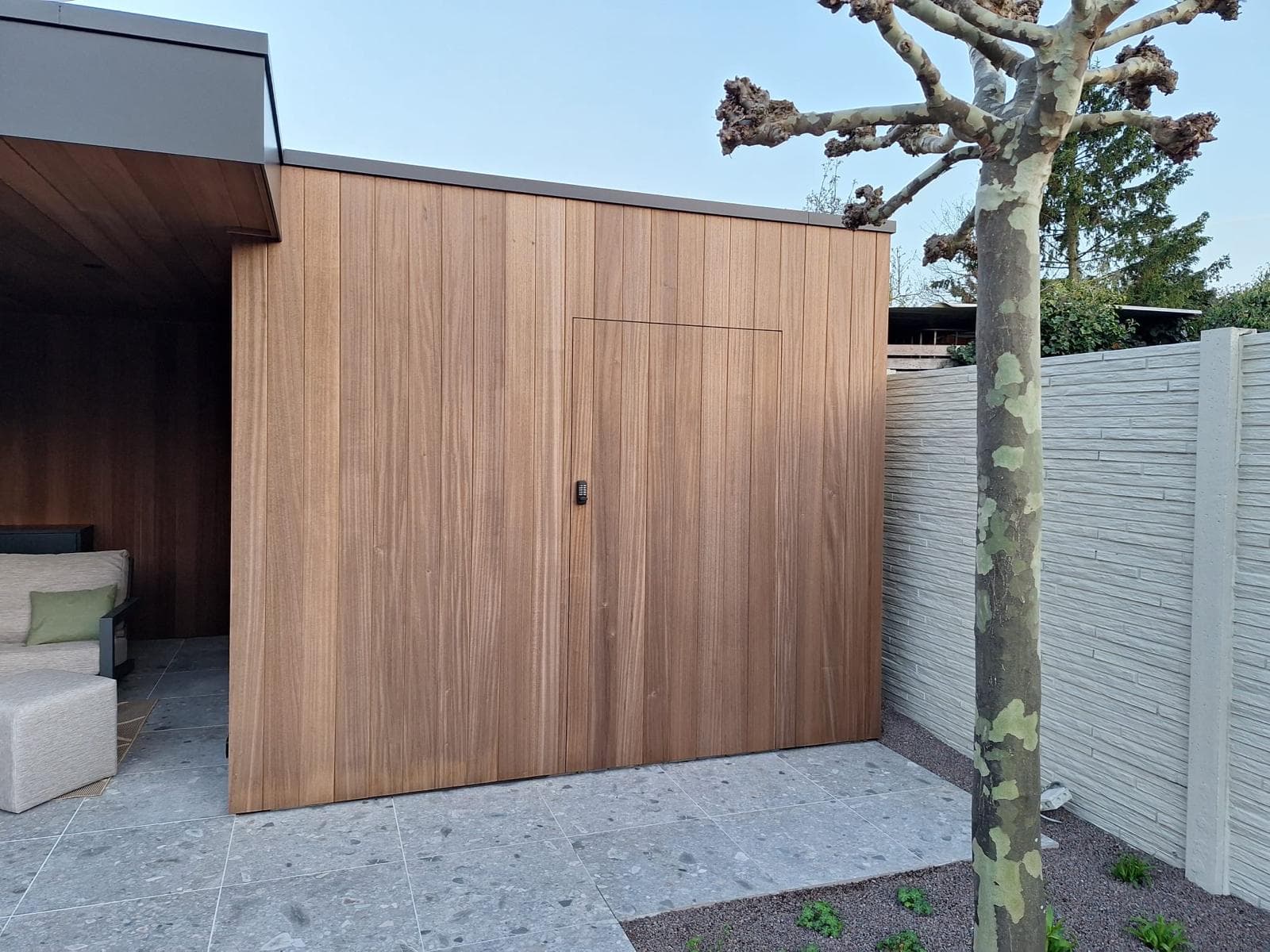 Naadloze Ayous houtbekleding van de berging met verborgen deur naast de overkapping