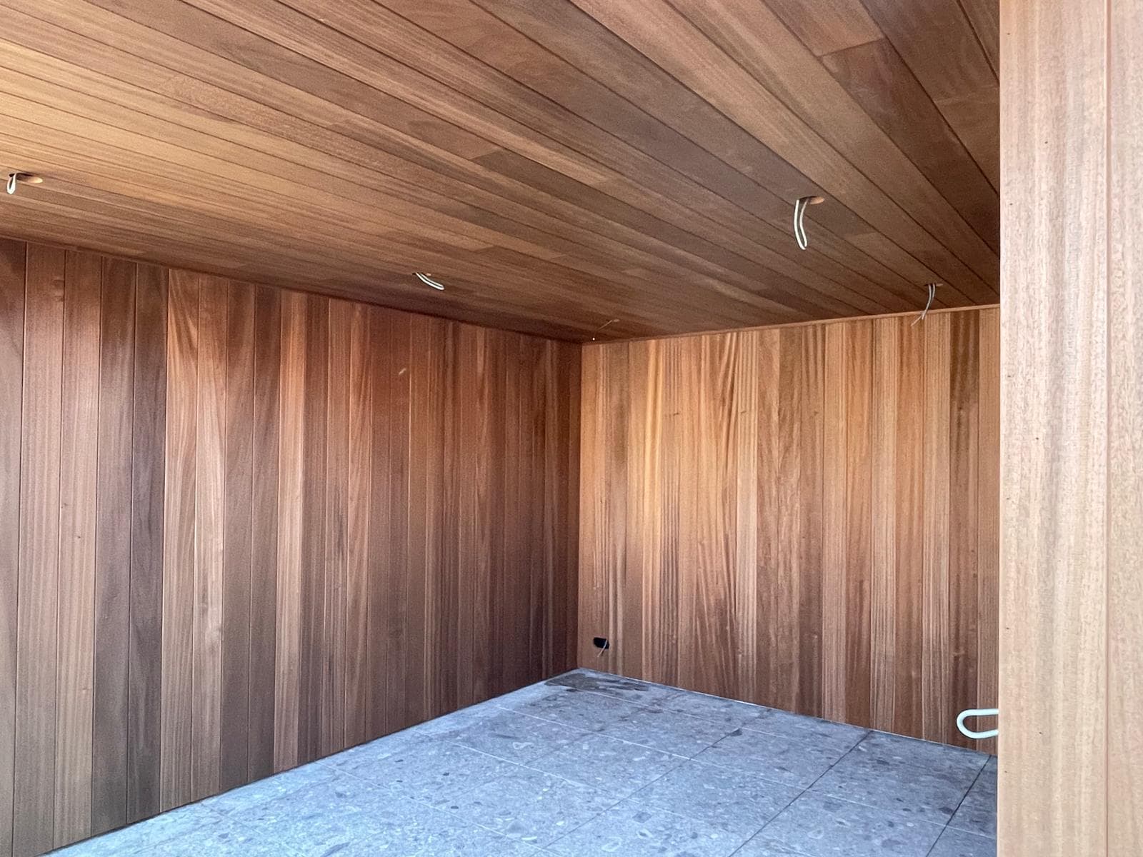 Detail van het warme houten Ayous plafond en wandbekleding onder de overkapping