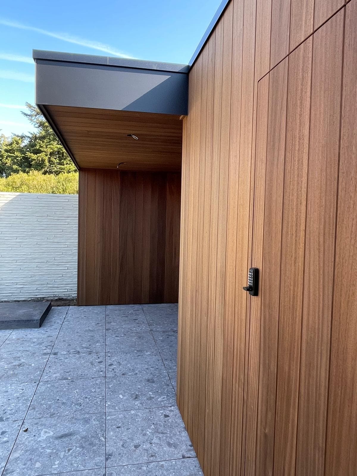 Detail van de antraciet dakrand en Ayous houtbekleding met codeslot op de bergingsdeur