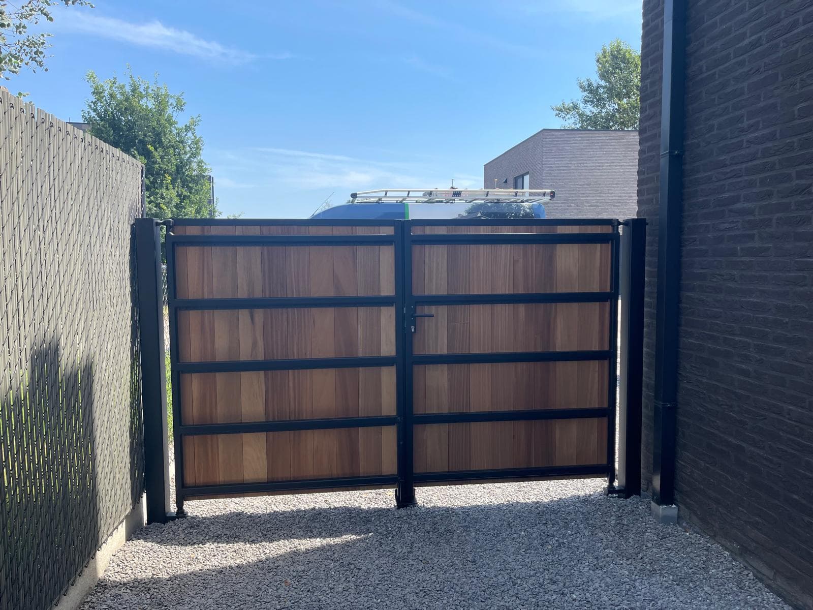 Constructiezijde van de poort: zwart stalen frame met horizontale regels en Ayous-panelen ertussen
