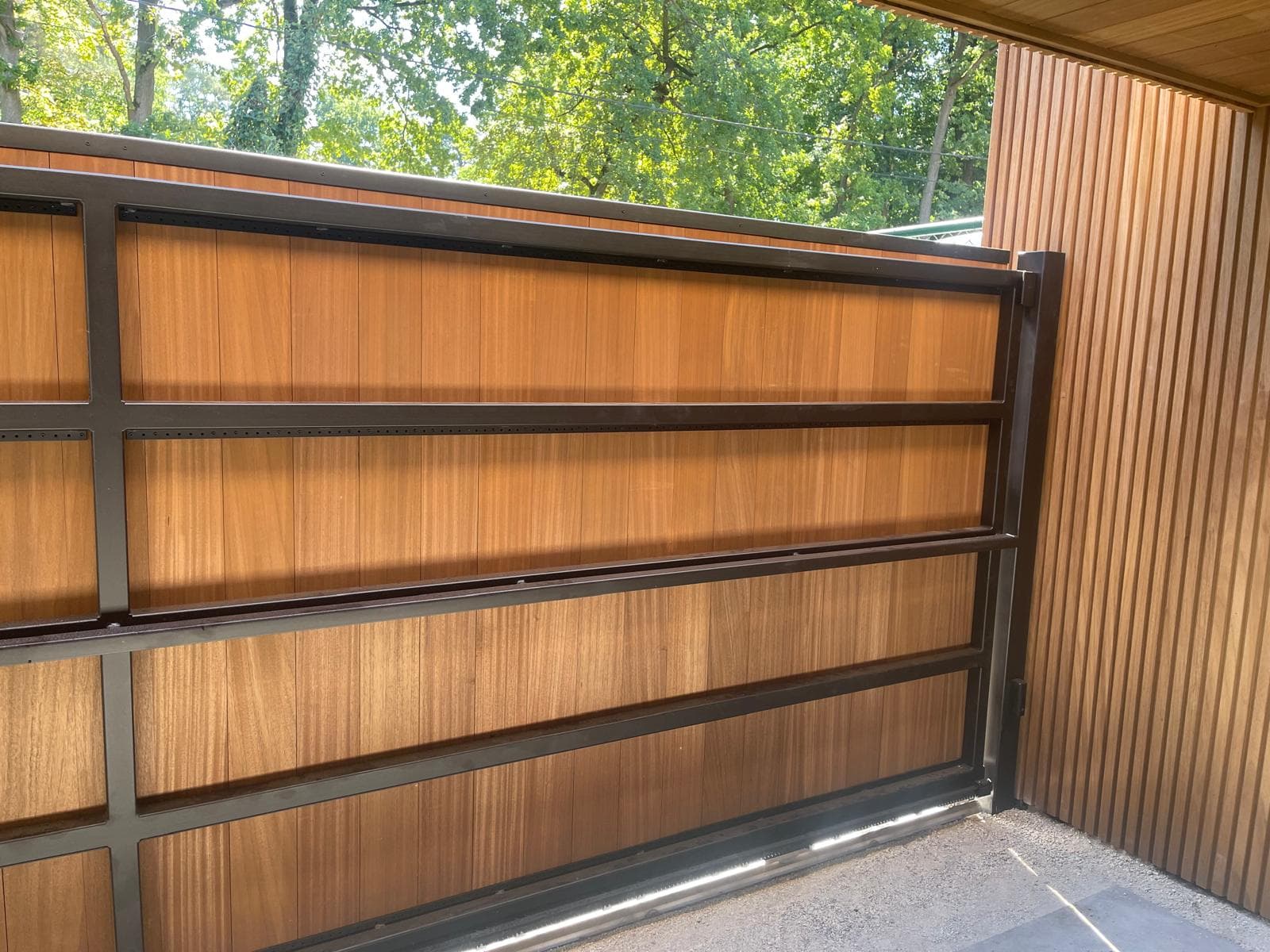Detail van de schuifpoort met zwart metalen frame en houten panelen