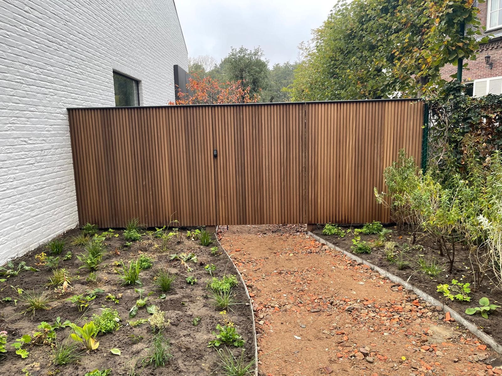 Houten schutting in thermisch Ayous met geïntegreerd poortje en aangelegde tuin, WoPa Construction
