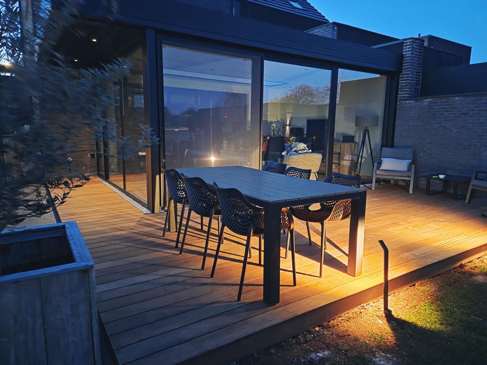 Houten Tali terras bij schemering met grondverlichting en zwarte eetset