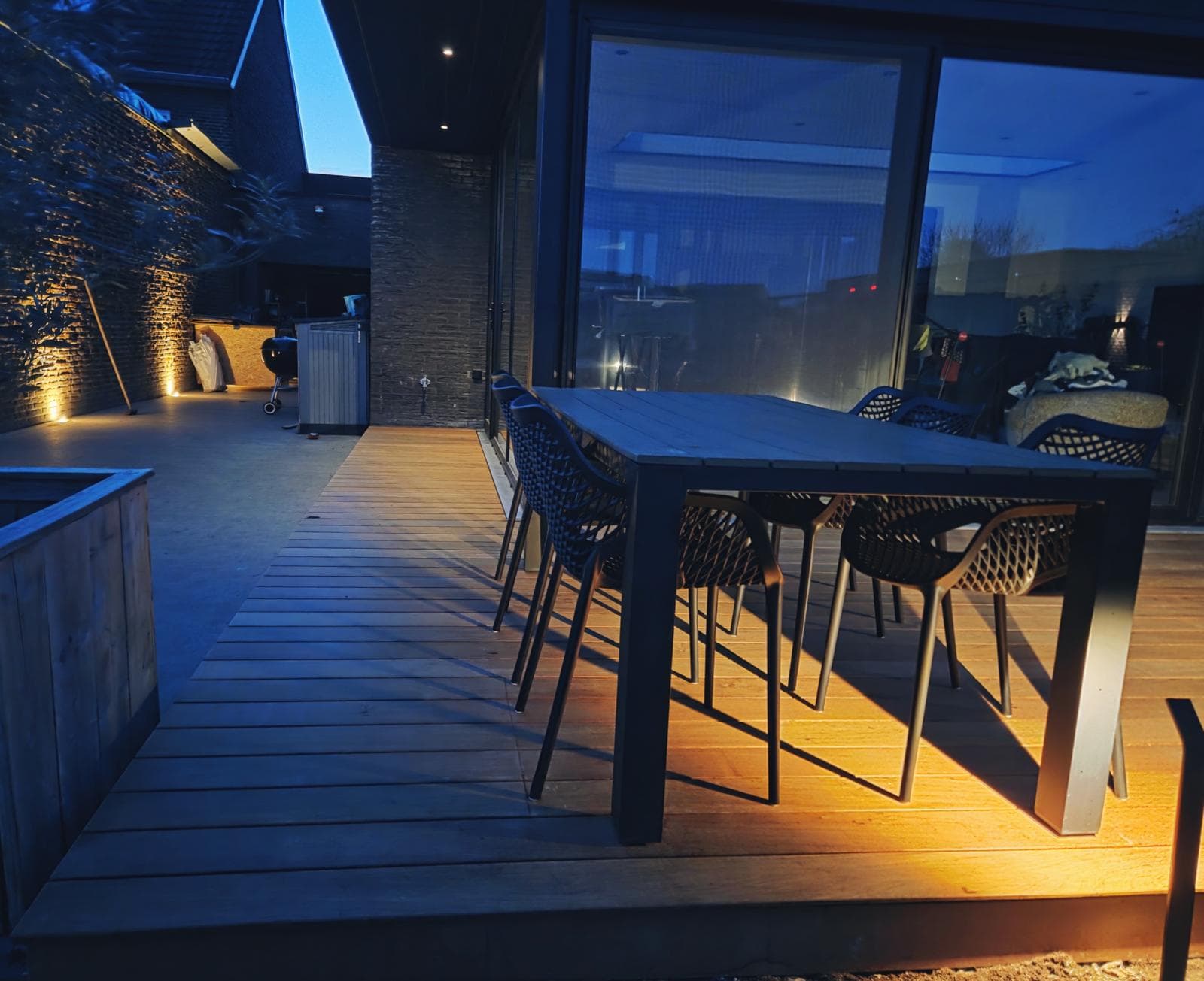 Tali terras met eettafel in het blauwe uur, verlicht door warme grondspots
