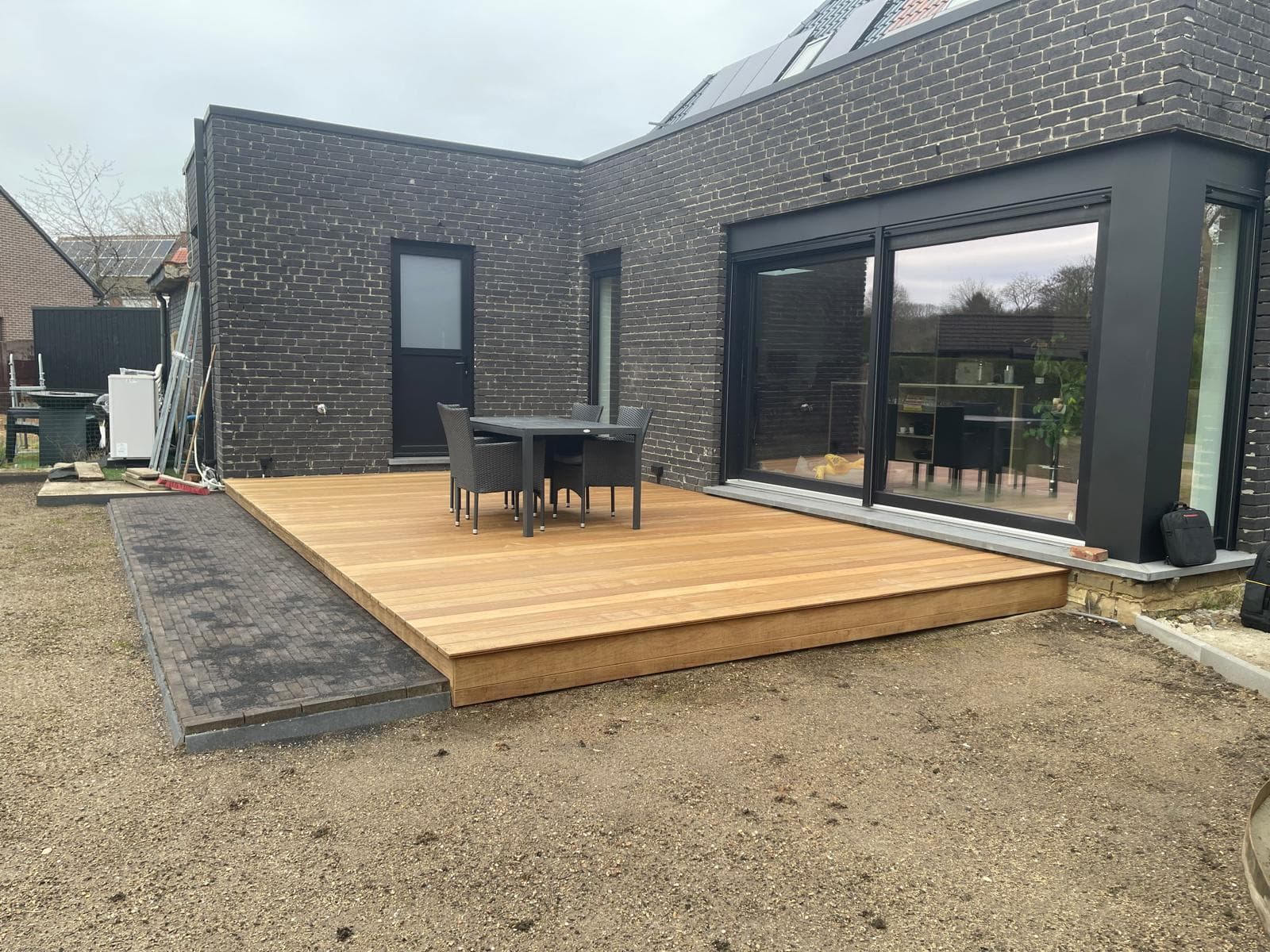 Volledig afgewerkt Tali terras met eettafel tegen een zwarte gevel, afgezet met klinkers