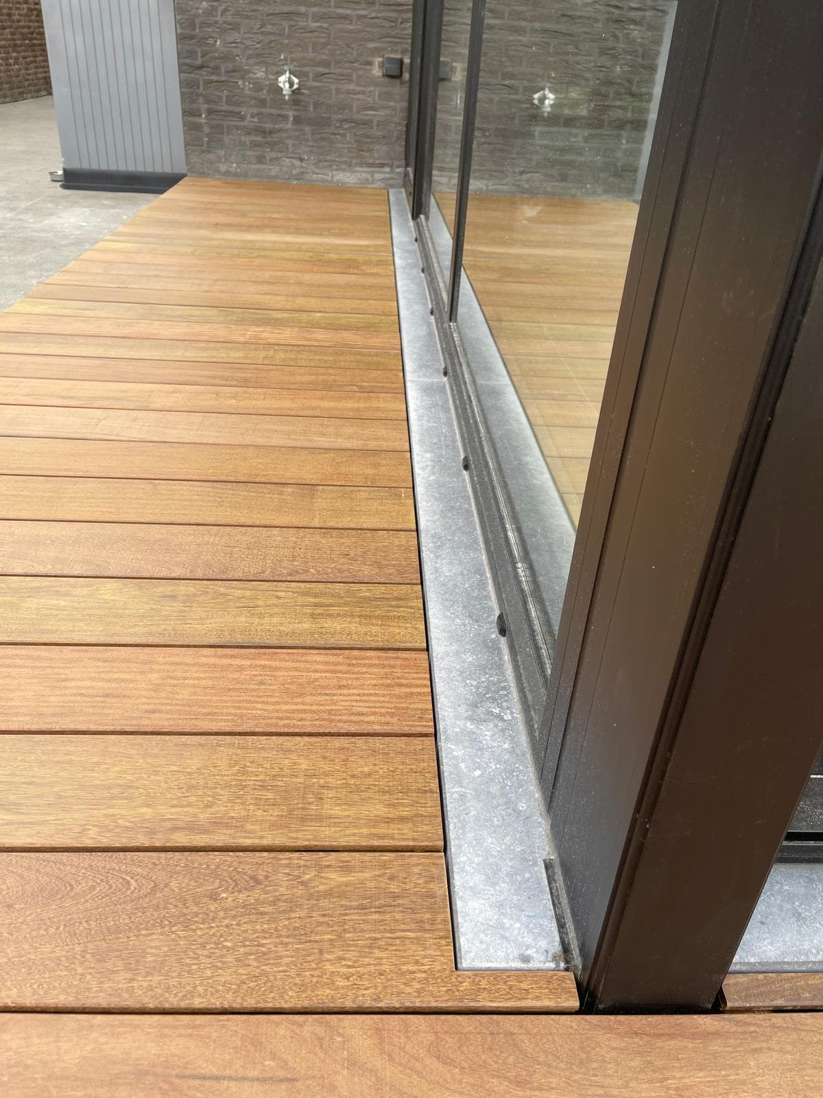 Warm gekleurd Tali terras dat aansluit op een houten plantenbak met olijfboom