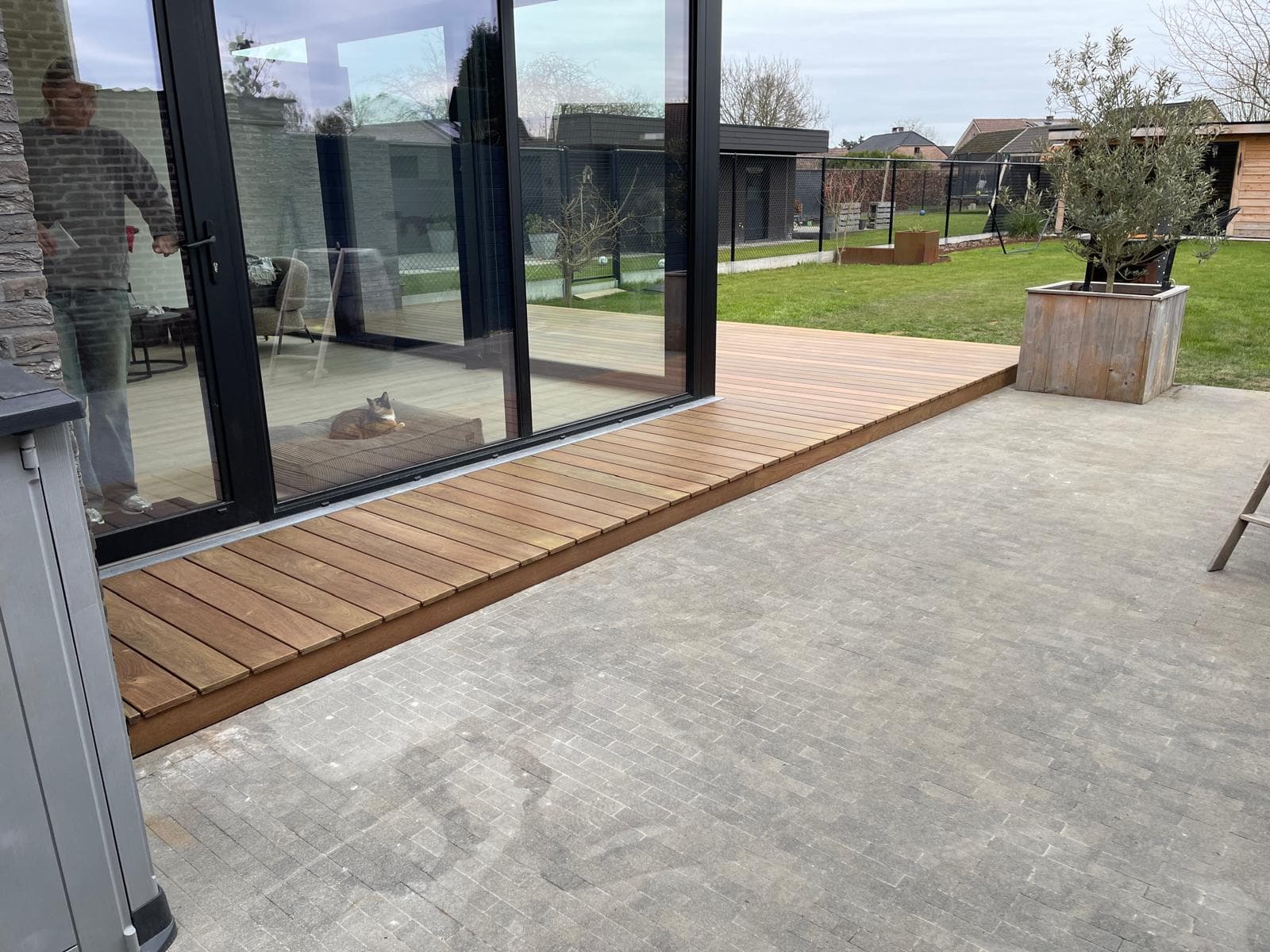Detail van strak gelegde Tali hardhouten planken langs de drempel van een schuifpui