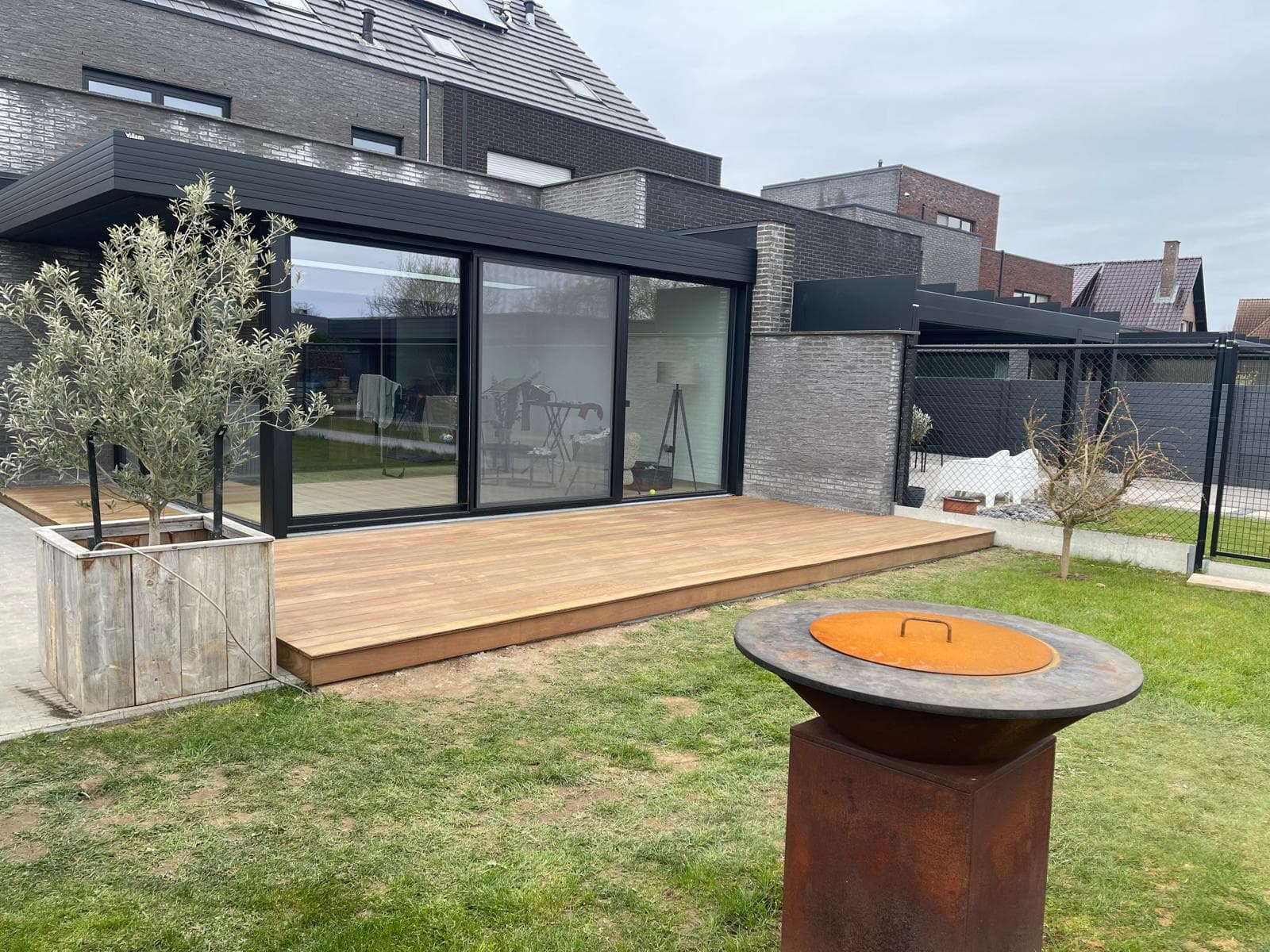 Strak afgewerkt Tali hardhouten terras langs een moderne aanbouw met grote schuifpui, WoPa Construction
