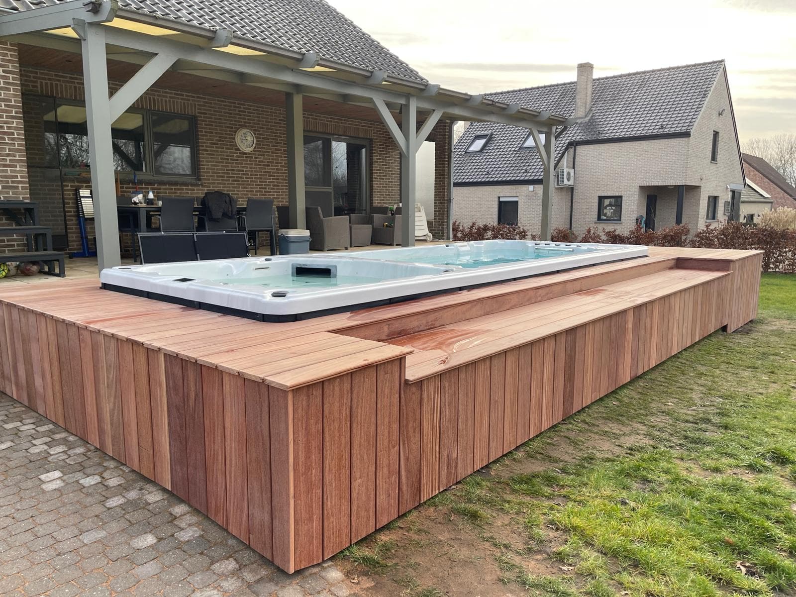 Verhoogd terras in Cumaru hardhout met geïntegreerde swim-spa en zitrand, WoPa Construction