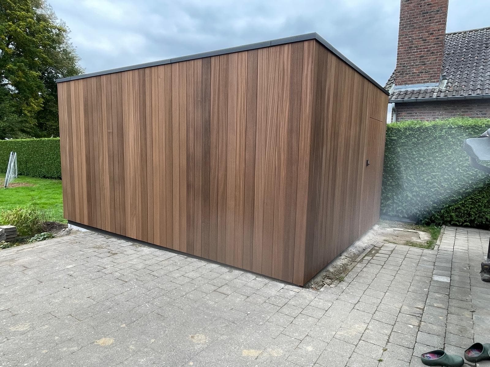 Zijaanzicht van de tuinberging met verticale gevelbekleding op terras