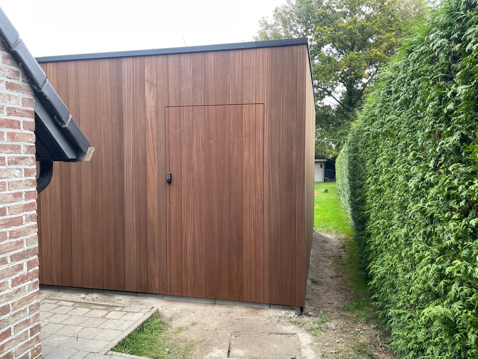 Naadloos in de houten gevel verwerkte toegangsdeur met codeslot