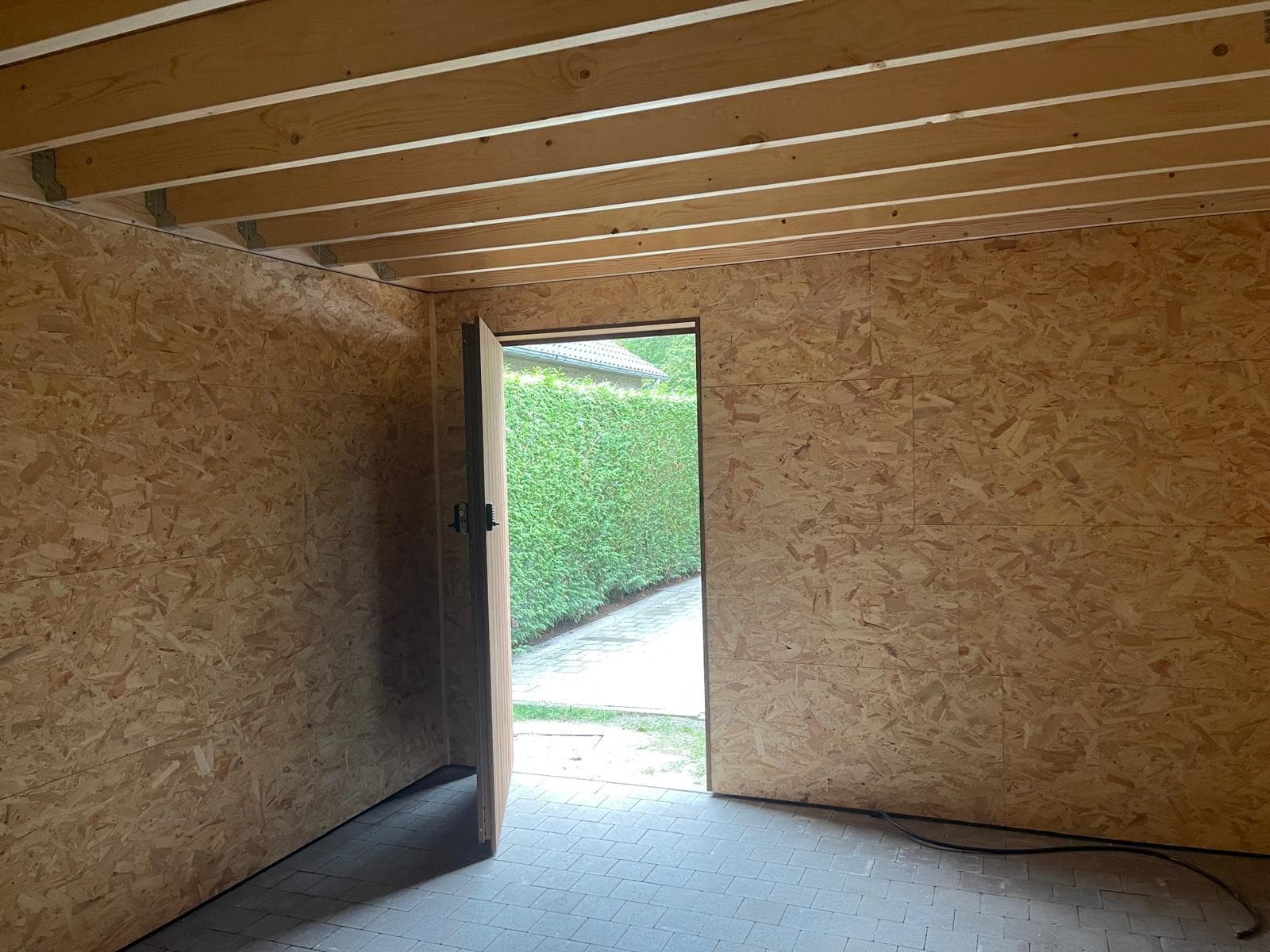 Interieur van de tuinberging met openstaande deur en zicht op de tuin
