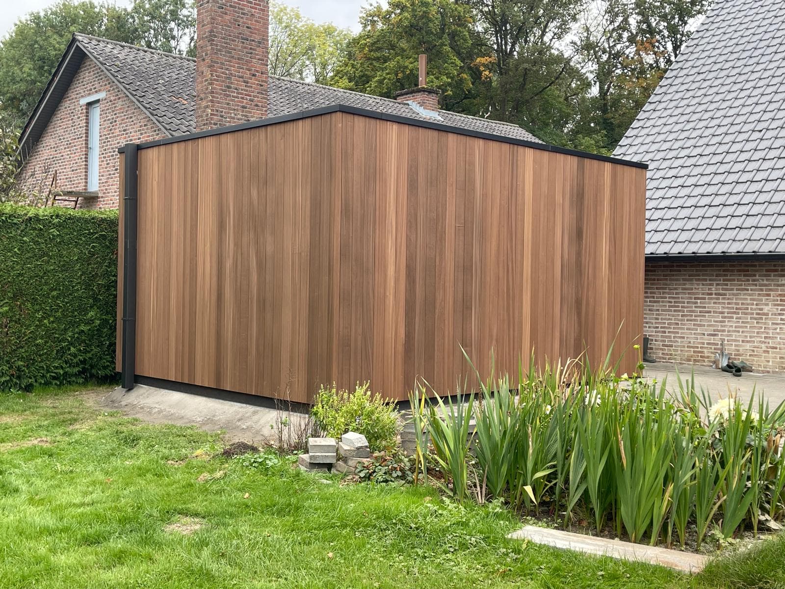 Moderne tuinberging in Ayous thermo classic met platdak in een aangelegde tuin in Alken, WoPa Construction