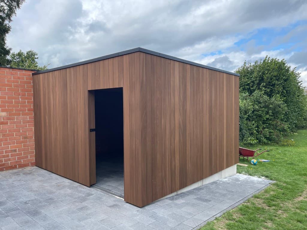 Tuinberging met open Ayous-deur tegen de bakstenen garage