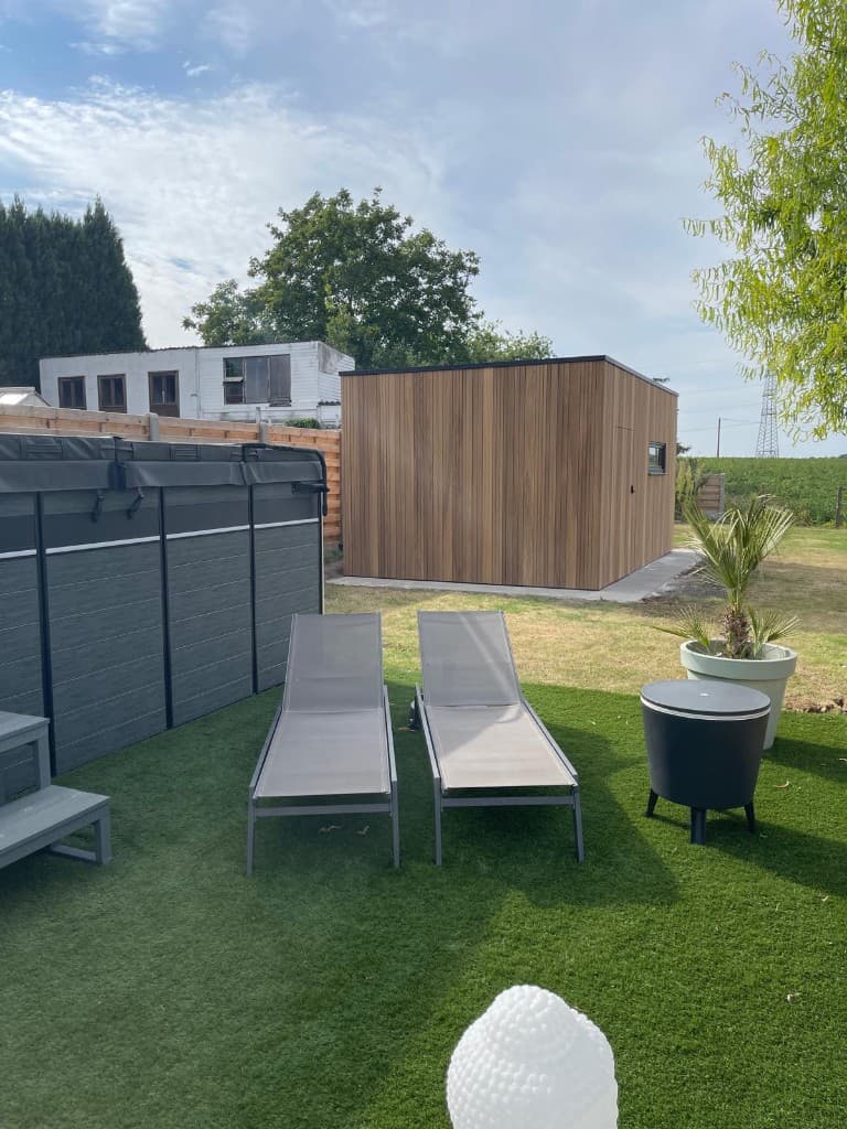 Tuinberging in de tuin bij het zwembad met ligbedden op kunstgras