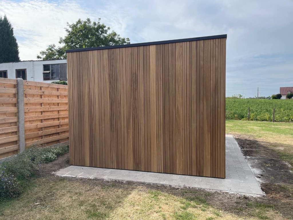 Tuinberging op klinkers naast de schutting met zicht op het veld