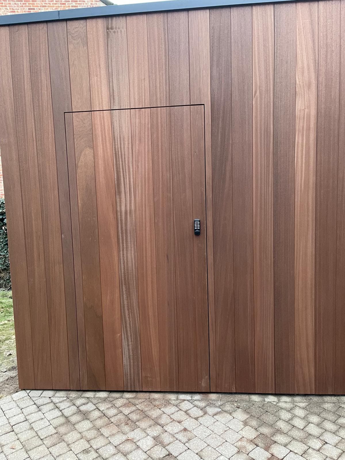 Hoekaanzicht van het tuinhuisje met deurzijde en strakke platte dakrand
